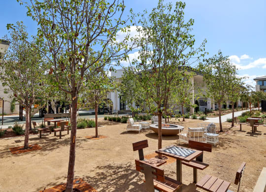 a courtyard with benches and trees and a building in the background at The Max on Jefferson Apartments, California, 92562