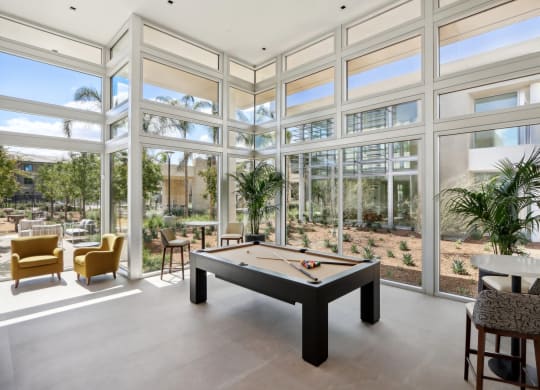 a billiards table in a room with glass walls at The Max on Jefferson Apartments, Murrieta