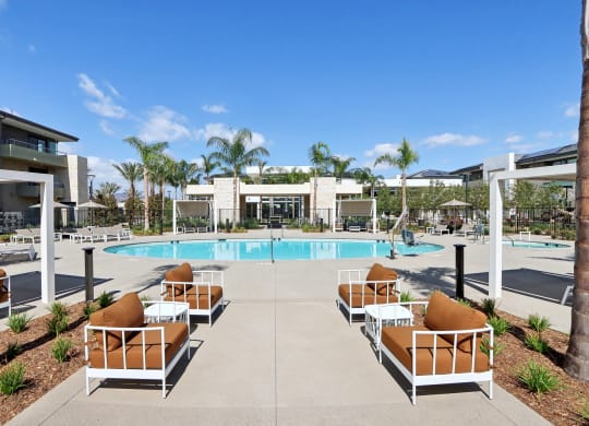 a swimming pool with lounge chairs and palm trees at the resort at The Max on Jefferson Apartments, Murrieta, CA