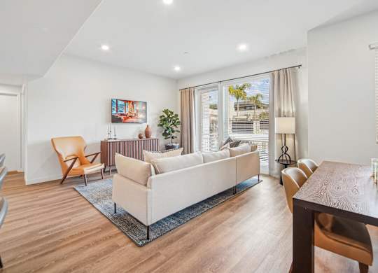 A living room with a white couch and a wooden table. at The Max on Jefferson Apartments, Murrieta, California