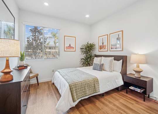 A bedroom with a bed, nightstand, and lamp at The Max on Jefferson Apartments, Murrieta, CA
