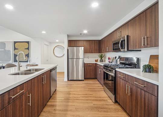A modern kitchen with wooden cabinets and stainless steel appliances. at The Max on Jefferson Apartments, California, 92562