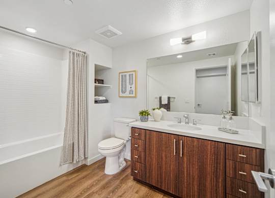 A bathroom with a toilet, sink, and mirror. at The Max on Jefferson Apartments, California