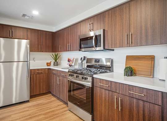 A modern kitchen with wooden cabinets and stainless steel appliances. at The Max on Jefferson Apartments, Murrieta, 92562