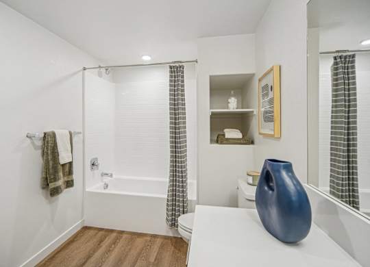 A white bathroom with a blue vase on the counter. at The Max on Jefferson Apartments, Murrieta