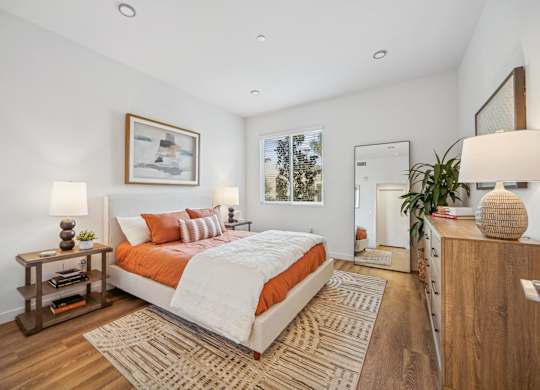 A bedroom with a large bed and a wooden nightstand at The Max on Jefferson Apartments, Murrieta, California