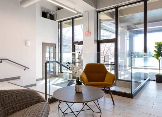a living room with a yellow chair and a table at The Residences at Tesson Ridge, Saint Louis