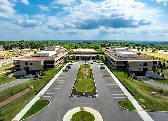 A large, modern building complex with a parking lot in front.