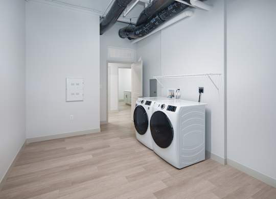 A white washing machine is in a room with wooden floors.