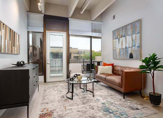 A living room with a brown couch, a coffee table, and a large painting on the wall.