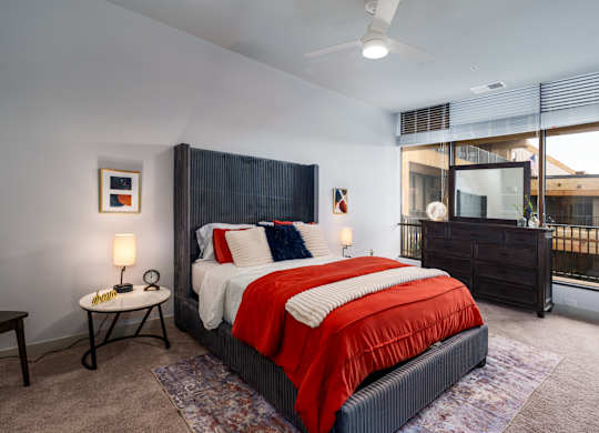 A bedroom with a large bed and a window overlooking a balcony.