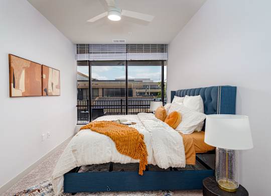 A bedroom with a bed, a lamp, and a painting on the wall.