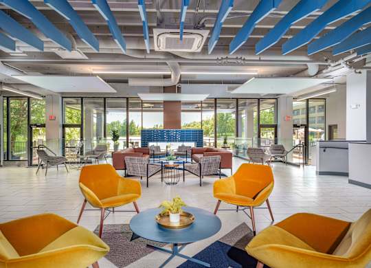 a lobby with yellow chairs and tables and a blue pillar