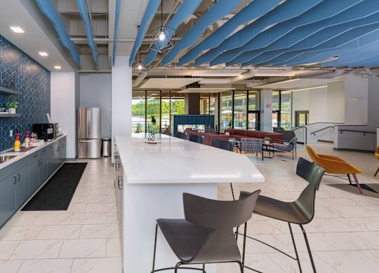 A modern kitchen with a white island and black chairs.