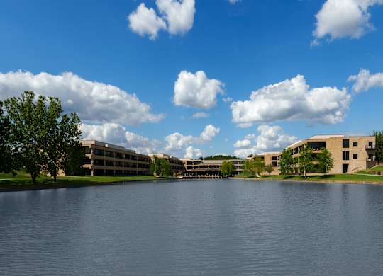 A large body of water with a building in the background and trees on the left.