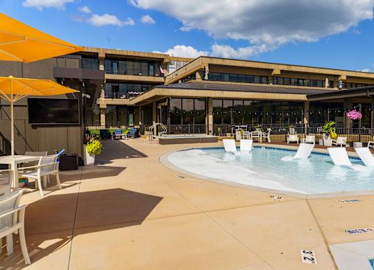 A large outdoor pool area with sun loungers and a building in the background.