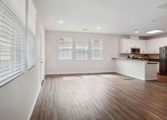 an empty living room with a kitchen in the background at Arrive at Rancho Belago, Moreno Valley, CA