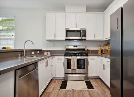 a kitchen with white cabinets and stainless steel appliances at Rancho Belago, Moreno Valley, 92555
