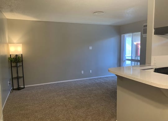 an empty room with a table and a lamp  at Dwell Apartment Homes, Riverside, CA, 92507