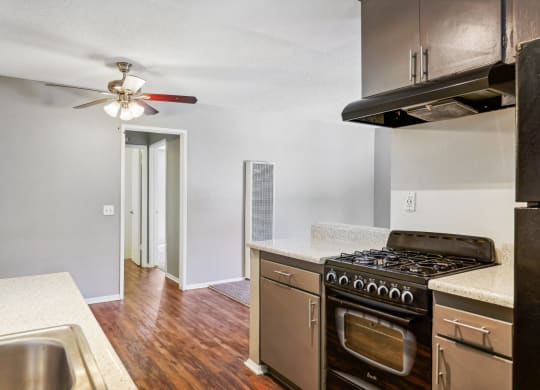 an empty kitchen with stainless steel appliances and a ceiling fan