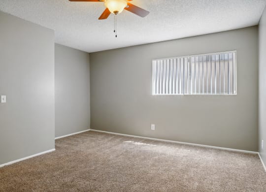 an empty living room with a ceiling fan and a window