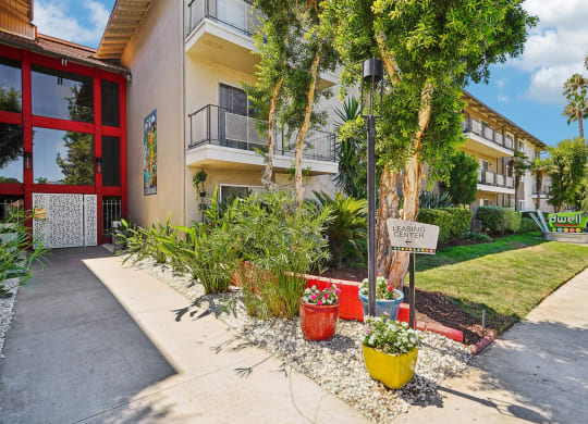 a sidewalk in front of a building with plants and trees
