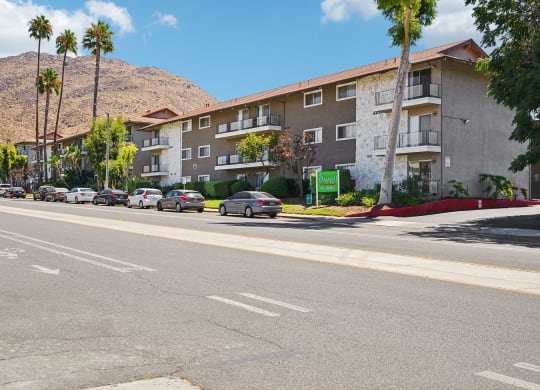 a city street with cars parked in front of an apartment building
