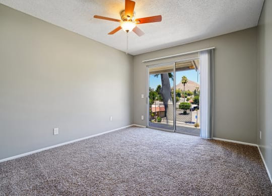 an empty living room with a ceiling fan and a door to a patio