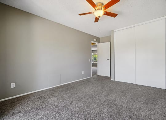 an empty living room with white walls and a ceiling fan