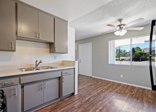 an empty kitchen with stainless steel appliances and a ceiling fan