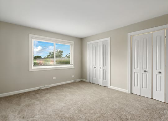 a bedroom with two closets and a window at The Hinsdale, Hinsdale, 60521