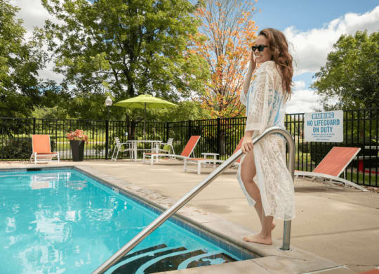 a woman standing next to a pool in a white dress
