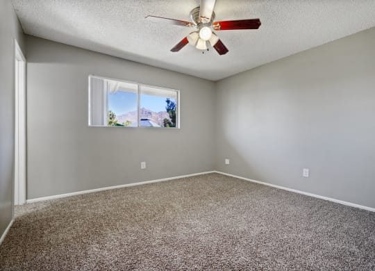 an empty room with a ceiling fan and a window