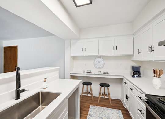 A kitchen with white cabinets and a stainless steel sink.
