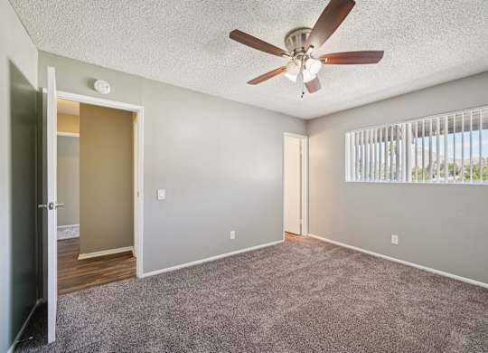 A room with a ceiling fan and a window with blinds.