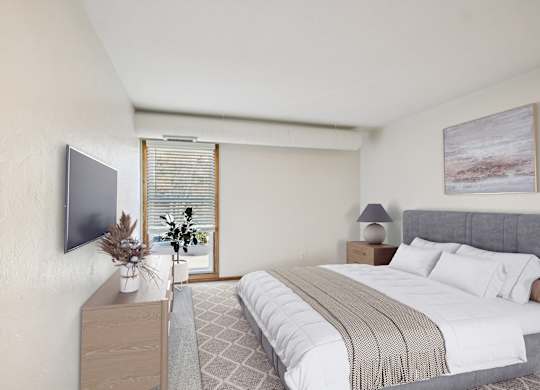 A bedroom with a large bed and a television on the wall.