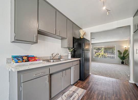 A kitchen with a black refrigerator and wooden floors.