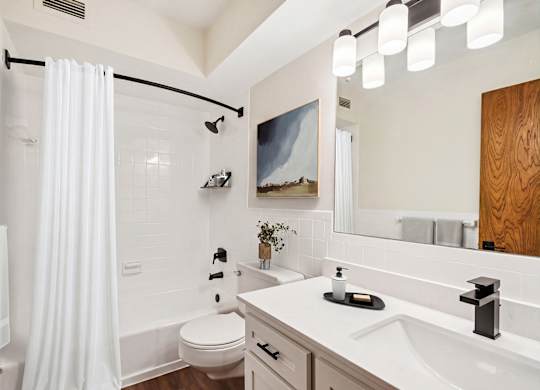 A white bathroom with a white toilet, a white sink, and a white shower curtain.