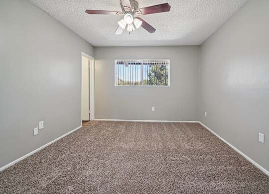 A room with a ceiling fan and carpeted floor.