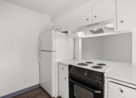 A white kitchen with a refrigerator, oven, and stove.