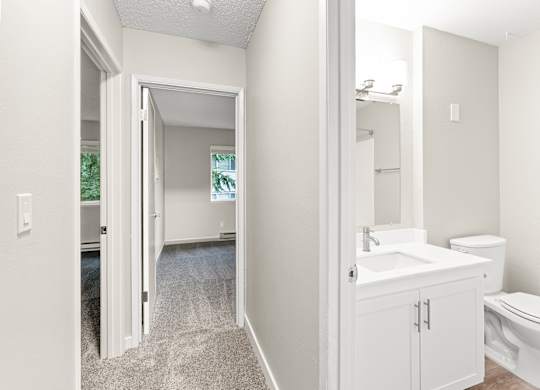A bathroom with a toilet, sink, and mirror.