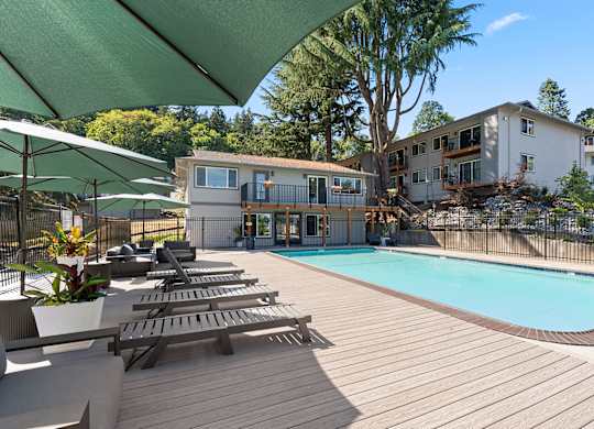 A pool surrounded by a deck with sun loungers and umbrellas.