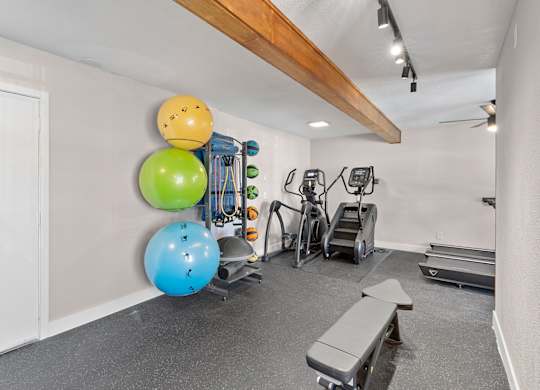 A gym with a bench, weights, and exercise balls.
