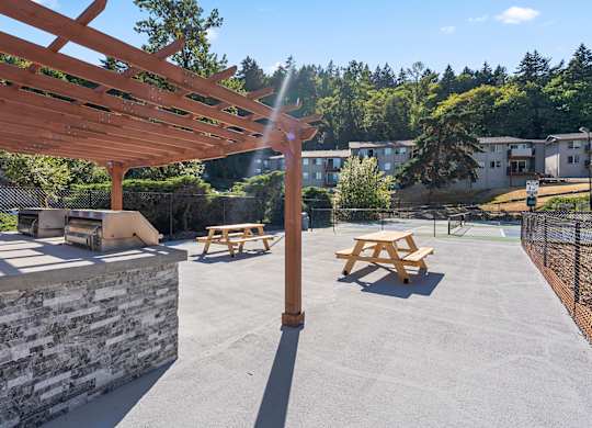 A wooden pergola with picnic tables underneath it.