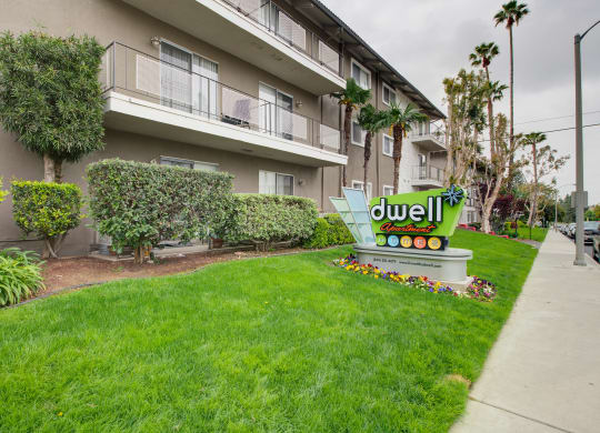 a lawn with a sign in front of an apartment building at Dwell Apartment Homes, Riverside, CA, 92507