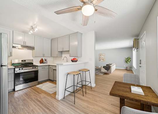 A kitchen with a refrigerator, stove, and bar stools.