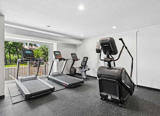 Fitness room with a treadmill, elliptical trainer, and a stationary bike.