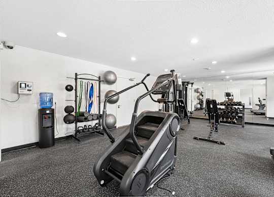 A gym with a treadmill, exercise bike, and weights.