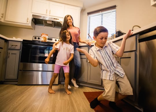 a woman and two children standing in a kitchen