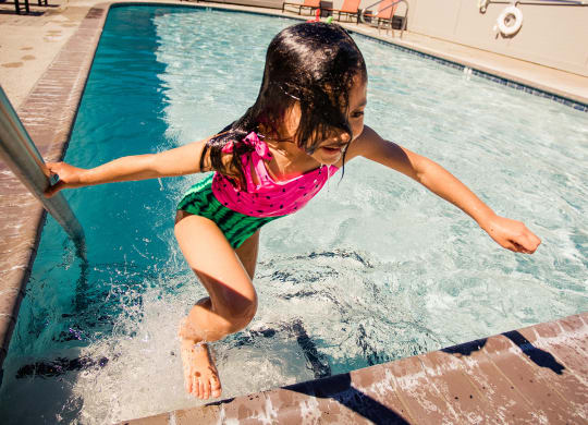 a little girl jumping into a swimming pool